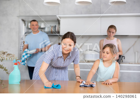 girl helping mother to wipe kitchen countertop girl helping mother to wipe kitchen countertop 140298061