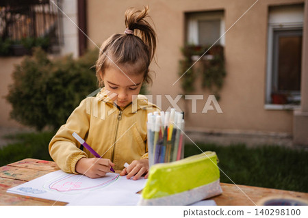 Young girl drawing on paper with marker pens outdoor 140298100