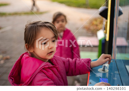 Young child playing arcade game outdoors with friends Young child playing arcade game outdoors with friends 140298101