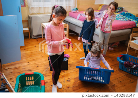 Children helping with laundry sorting clothes in bedroom Children helping with laundry sorting clothes in bedroom 140298147