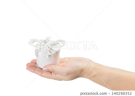 Woman's hand holding a gift box on her palm with the white background. Woman's hand holding a gift box on her palm with the white background. 140298352