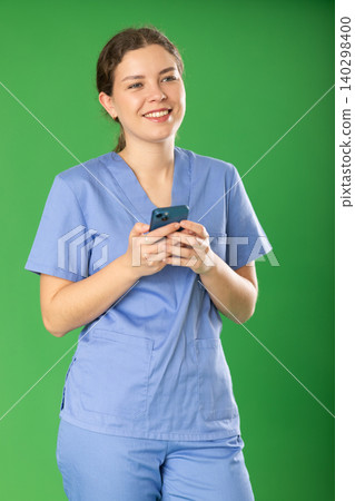 Nurse in uniform scrolls through her smartphone while reading social media 140298400