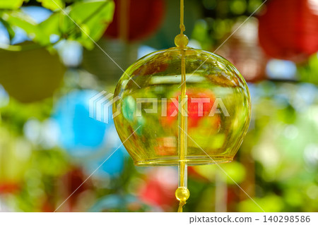 夏日陽光灑在閃閃發光的翠綠植物間,黃色的風鈴叮噹作響。 夏日陽光灑在閃閃發光的翠綠植物間,黃色的風鈴叮噹作響。 140298586