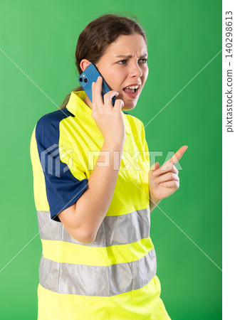 Portrait of professional female worker wearing high visibility polo emotionally talking to client by smartphone Portrait of professional female worker wearing high visibility polo emotionally talking to client by smartphone 140298613