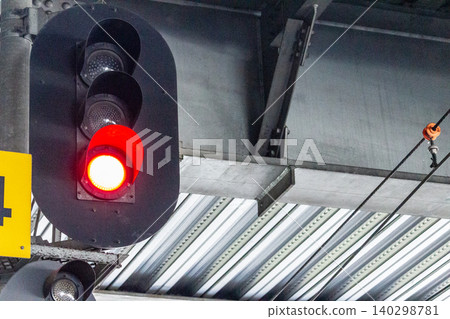 A red signal on a railway line and overhead wires on a station platform – an image of stopping. A red signal on a railway line and overhead wires on a station platform – an image of stopping. 140298781