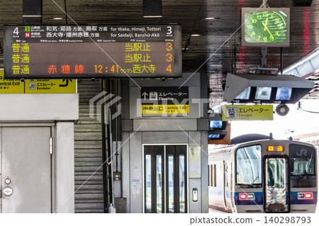 某地方城市的JR火車站月台、電子顯示器和停放的列車。 某地方城市的JR火車站月台、電子顯示器和停放的列車。 140298793