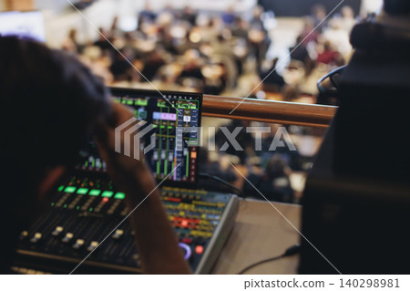 Lighting technician operator working on mixing console, workplace during live event, stage concert show broadcast, light mixer controller panel, sound technician with professional equipment at venue Lighting technician operator working on mixing console, workplace during live event, stage concert show broadcast, light mixer controller panel, sound technician with professional equipment at venue 140298981