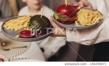 Waiter in uniform serving dishes and drinks on party, server carrying plates with food and beverages at the table, catering service on wedding reception, personnel in cafe restaurant, staff on event Waiter in uniform serving dishes and drinks on party, server carrying plates with food and beverages at the table, catering service on wedding reception, personnel in cafe restaurant, staff on event 140299071