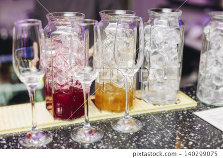 Barman mixing and pouring drinks and beverages, beautiful row line of different coloured lemonades in a jar, liquor alcohol cocktails on a party in bar, catering banquet on event, mocktails in a jug Barman mixing and pouring drinks and beverages, beautiful row line of different coloured lemonades in a jar, liquor alcohol cocktails on a party in bar, catering banquet on event, mocktails in a jug 140299075