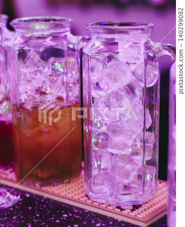 Barman mixing and pouring drinks and beverages, beautiful row line of different coloured lemonades in a jar, liquor alcohol cocktails on a party in bar, catering banquet on event, mocktails in a jug Barman mixing and pouring drinks and beverages, beautiful row line of different coloured lemonades in a jar, liquor alcohol cocktails on a party in bar, catering banquet on event, mocktails in a jug 140299082