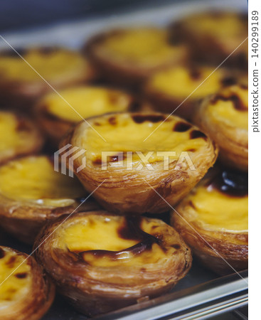 Pasteis and Pastel de nata, traditional Portuguese egg custard tart pasty cakes, dessert Pasteis de nata with different pastry in the cafe, bakery display window, Pastel de belem, Lisbon, Portugal Pasteis and Pastel de nata, traditional Portuguese egg custard tart pasty cakes, dessert Pasteis de nata with different pastry in the cafe, bakery display window, Pastel de belem, Lisbon, Portugal 140299189