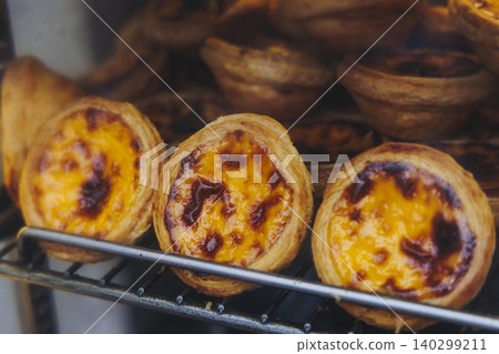 Pasteis and Pastel de nata, traditional Portuguese egg custard tart pasty cakes, dessert Pasteis de nata with different pastry in the cafe, bakery display window, Pastel de belem, Lisbon, Portugal Pasteis and Pastel de nata, traditional Portuguese egg custard tart pasty cakes, dessert Pasteis de nata with different pastry in the cafe, bakery display window, Pastel de belem, Lisbon, Portugal 140299211
