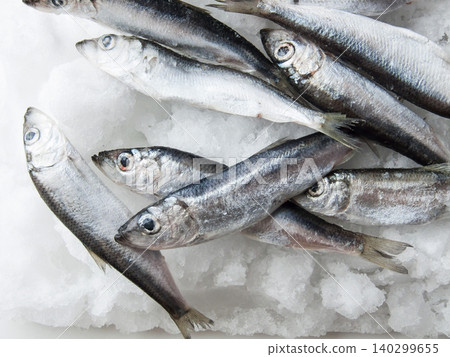 Frozen seafood anchovies and herring fish sprat on brick of ice and snow, shoaling fish on ice. Frozen seafood anchovies and herring fish sprat on brick of ice and snow, shoaling fish on ice. 140299655