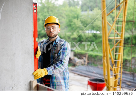 Construction worker checking wall level at building site Construction worker checking wall level at building site 140299686