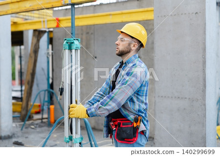Construction worker using surveying equipment on building site Construction worker using surveying equipment on building site 140299699