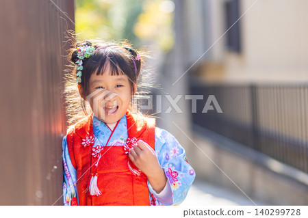 Joyful young Japanese girl in traditional kimono smiles brightly outdoors Joyful young Japanese girl in traditional kimono smiles brightly outdoors 140299728