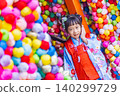 Young Japanese girl in traditional kimono smiles near colorful omikuji charms 140299729