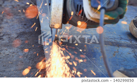 Worker using an angle grinder, cutting metal with sparks flying at construction site Worker using an angle grinder, cutting metal with sparks flying at construction site 140299850