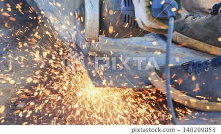 Industrial worker cutting metal with a power grinder creating bright sparks Industrial worker cutting metal with a power grinder creating bright sparks 140299853