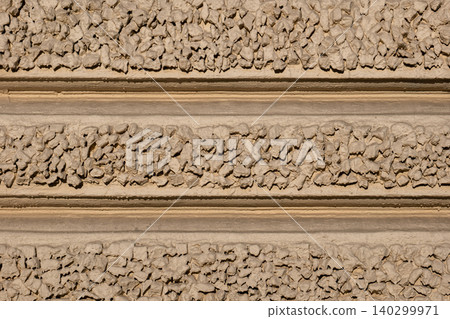 Rough concrete wall displaying aggregated pebble texture and horizontal stucco bands Rough concrete wall displaying aggregated pebble texture and horizontal stucco bands 140299971