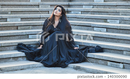Bangladeshi woman sitting on stairs in black dress, looking up, dreaming of future Bangladeshi woman sitting on stairs in black dress, looking up, dreaming of future 140300090