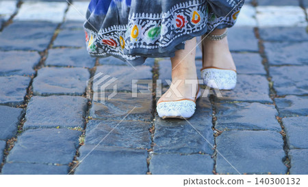 Indian woman walking on cobblestone street wearing traditional sari and shoes Indian woman walking on cobblestone street wearing traditional sari and shoes 140300132