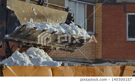 Excavator bucket loading white snow into dump truck, city street snow removal Excavator bucket loading white snow into dump truck, city street snow removal 140300187
