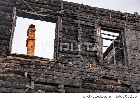 Charred wooden house wall after a fire destroying structure and leaving only chimney Charred wooden house wall after a fire destroying structure and leaving only chimney 140300219