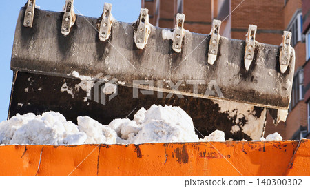 Excavator bucket moving snow into an orange truck during harsh winter conditions Excavator bucket moving snow into an orange truck during harsh winter conditions 140300302