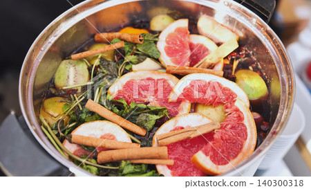 Warm mulled wine preparing with grapefruit slices, cinnamon sticks, and mint in a pot Warm mulled wine preparing with grapefruit slices, cinnamon sticks, and mint in a pot 140300318