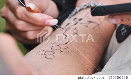 Arm getting a non-traditional chemical formula applied as creative body art for a festival Arm getting a non-traditional chemical formula applied as creative body art for a festival 140300326