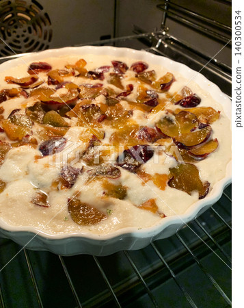 A gluten-free plum pie is baking in the oven. The clear white dish holds the pie that is warming up. The kitchen is filled with the sweet smell of baked fruit A gluten-free plum pie is baking in the oven. The clear white dish holds the pie that is warming up. The kitchen is filled with the sweet smell of baked fruit 140300534