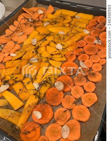 Vegetables including carrots, pumpkin and sweet potato are prepared on a baking tray ready to bake in the oven. The tray is lined and set on a stove surface Vegetables including carrots, pumpkin and sweet potato are prepared on a baking tray ready to bake in the oven. The tray is lined and set on a stove surface 140300565