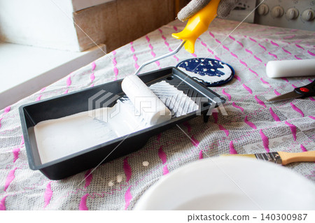 Paint roller and tray on table. Man is ready to do light makeover in his house. Home transformation. Creative home care concept Paint roller and tray on table. Man is ready to do light makeover in his house. Home transformation. Creative home care concept 140300987