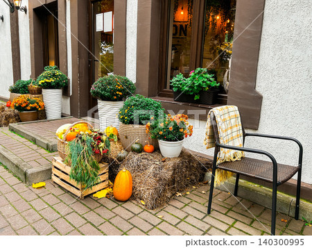 Halloween decoration of cafe entrance celebrating October holidays. Pumpkins and flowers on restaurant terrace Halloween decoration of cafe entrance celebrating October holidays. Pumpkins and flowers on restaurant terrace 140300995