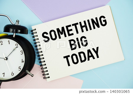Something Big Today text written on notepad with alarm clock flat lay on multicolor pastel background 140301065