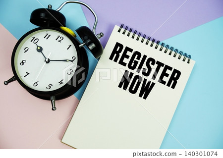 Register Now text written on notepad with alarm clock flat lay on multicolor pastel background 140301074