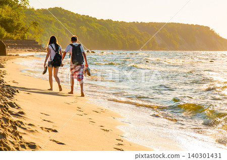 Couple Man And Woman Walk On Sandy Beach Sea Ocean Water pond, Summer Landscape Couple Man And Woman Walk On Sandy Beach Sea Ocean Water pond, Summer Landscape 140301431