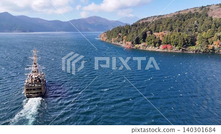 從空中俯瞰,一艘海盜船在秋色正濃的蘆之湖上航行,背景是富士山。 從空中俯瞰,一艘海盜船在秋色正濃的蘆之湖上航行,背景是富士山。 140301684
