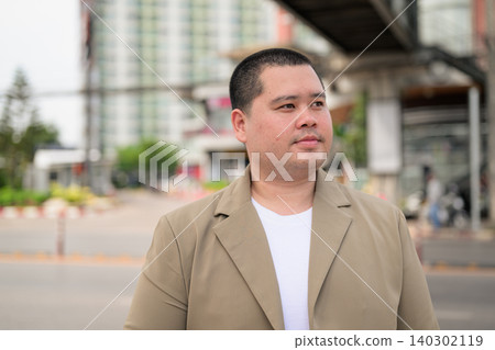 Plus size Isan Thai businessman standing outdoors on a city street Plus size Isan Thai businessman standing outdoors on a city street 140302119