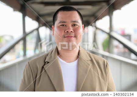 Plus size Isan Thai man looking at camera on a bridge walkway Plus size Isan Thai man looking at camera on a bridge walkway 140302134
