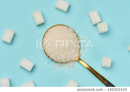 A golden spoon with crystal sugar surrounded by white cubes of refined sugar on a blue background A golden spoon with crystal sugar surrounded by white cubes of refined sugar on a blue background 140302420