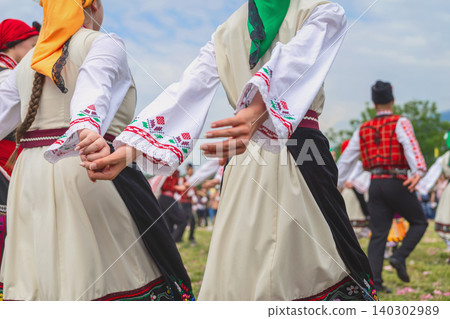 Dancers in folk costumes hold hands during Kazanlak Rose Festival in Bulgaria. Festival highlights Rose picking in Valley of Roses. Folk dance, identity, d community tradition Dancers in folk costumes hold hands during Kazanlak Rose Festival in Bulgaria. Festival highlights Rose picking in Valley of Roses. Folk dance, identity, d community tradition 140302989