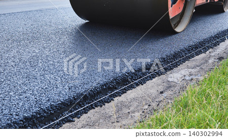Road roller compacting fresh asphalt during highway construction and infrastructure development 140302994