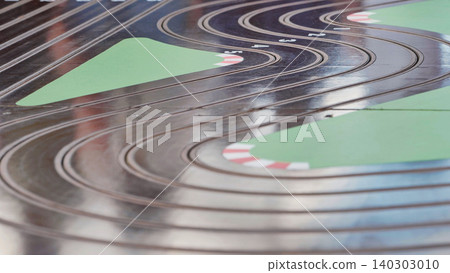 White and pink toy cars competing on a slot car track during a sports day, providing entertainment and excitement. 140303010