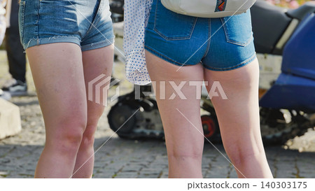 Rear view of two young women in blue denim shorts standing outdoors Rear view of two young women in blue denim shorts standing outdoors 140303175