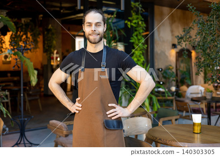 Confident male cafe owner standing with hands on hips smiling Confident male cafe owner standing with hands on hips smiling 140303305