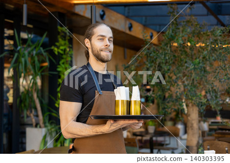 Male restaurant employee holding tray with napkins Male restaurant employee holding tray with napkins 140303395