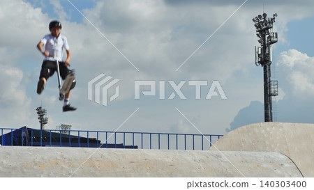 Boy performing scooter jump in skatepark, extreme sport training 140303400