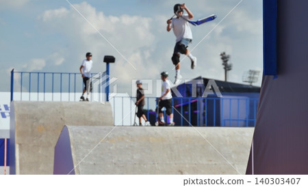 Young rider jumping high on a scooter in a skate park, showcasing action and skill Young rider jumping high on a scooter in a skate park, showcasing action and skill 140303407